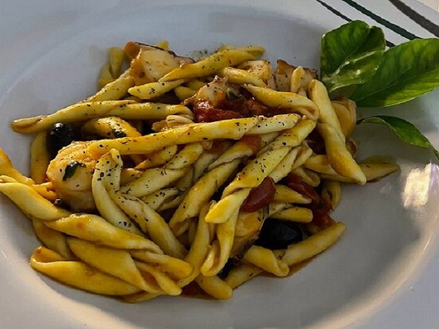 Handmade pasta with tomato, black olives and a basil leaf