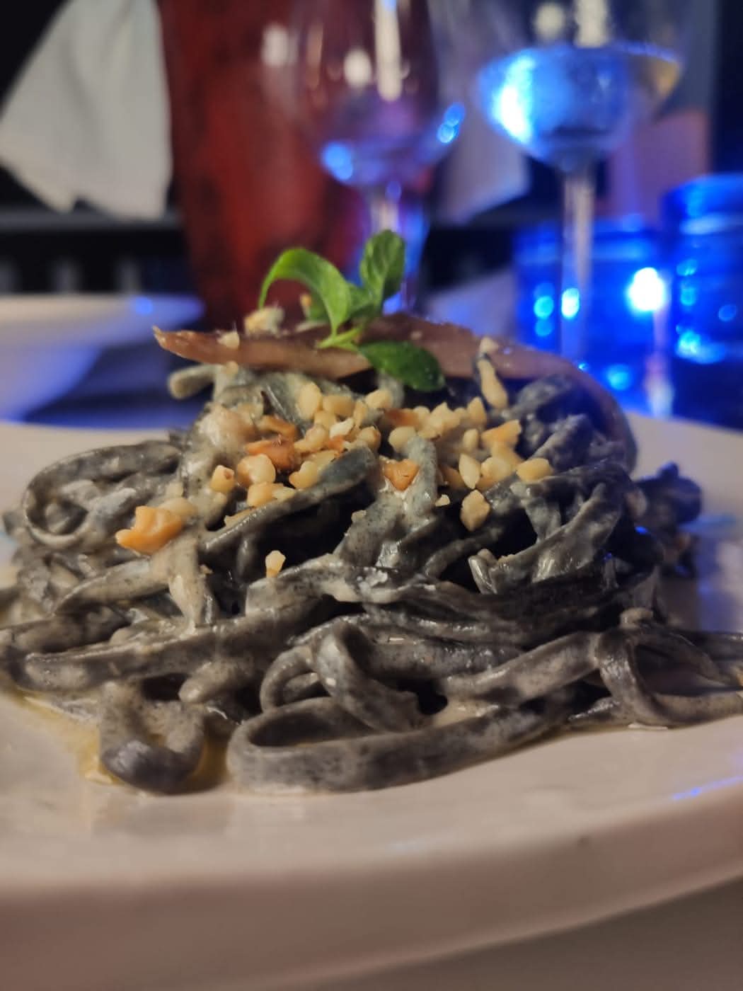 Dark pasta with a creamy sauce, crumbs and a basil leaf