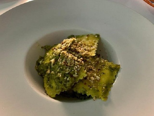 Green ravioli sprinkled with crushed nuts