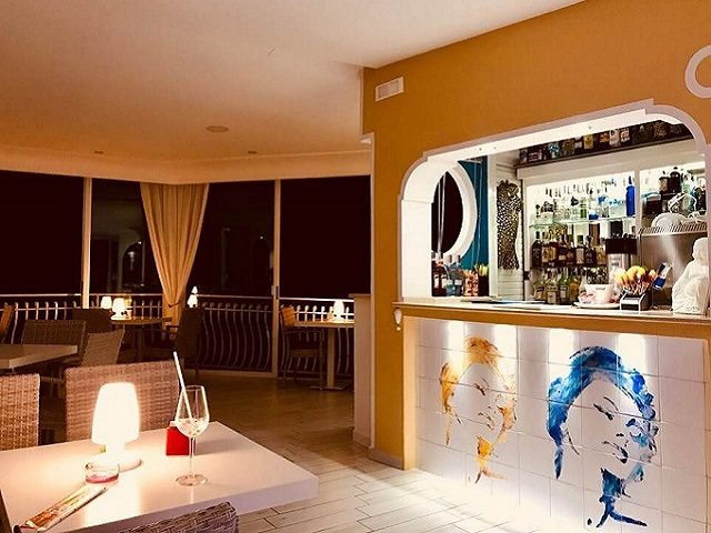The dining room at night, with the bar and a painted tile portrait