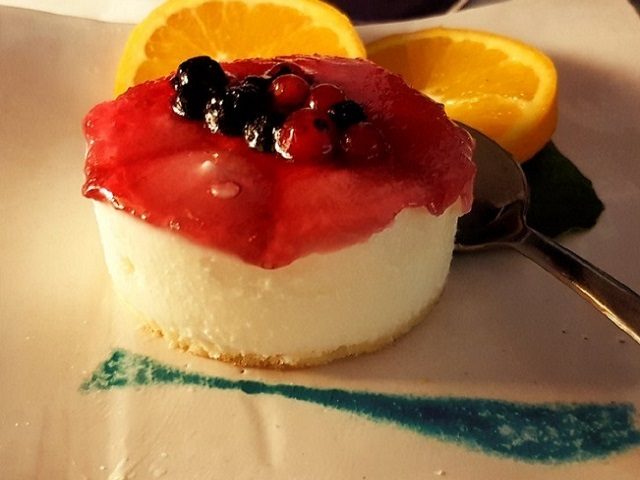 Cream dessert with a red berry topping and orange slices