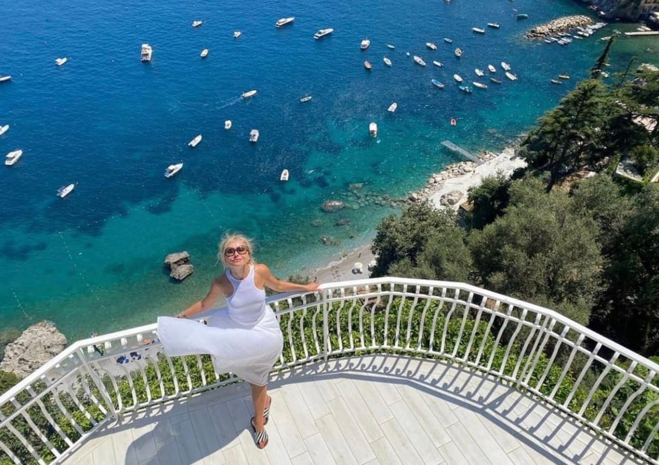 Guest on the panoramic terrace above the bay, with boats on the turquoise sea