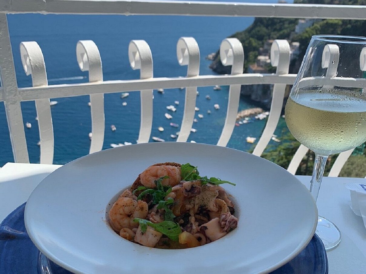 Seafood pasta and a glass of white wine on the terrace overlooking the sea