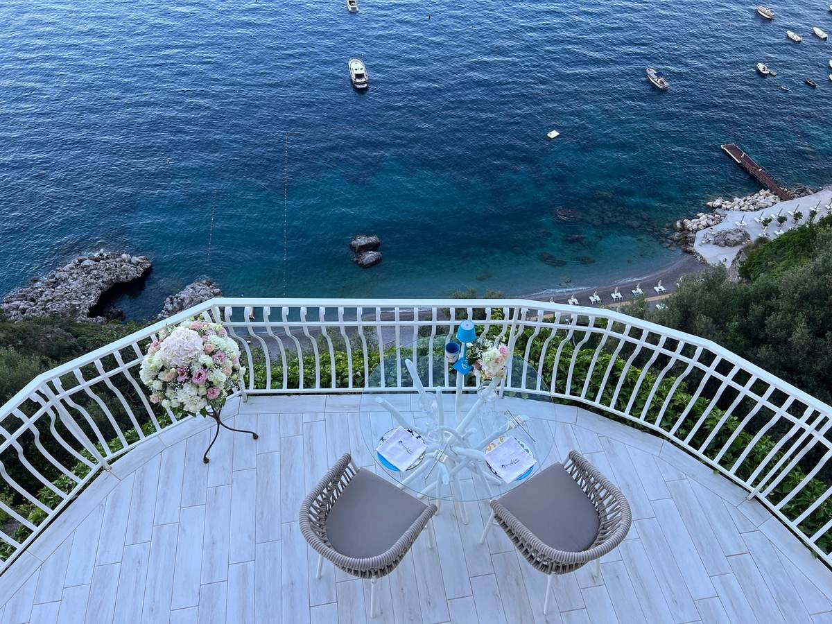 Private terrace set for two above the sea, with boats on the water below